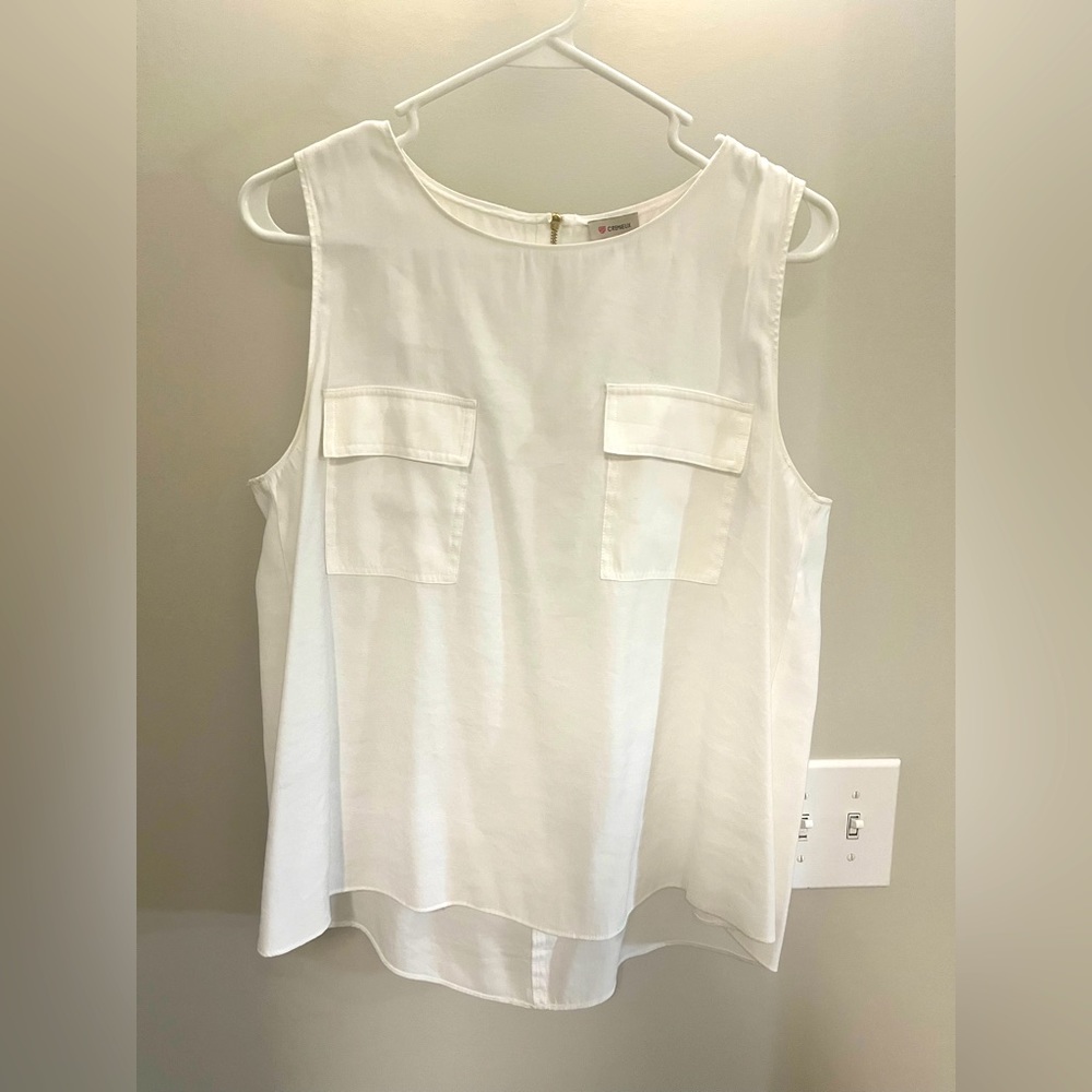 White sleeveless top two pockets on front and gold zipper on back.